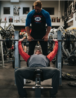 Personal trainer assisting client at gym
