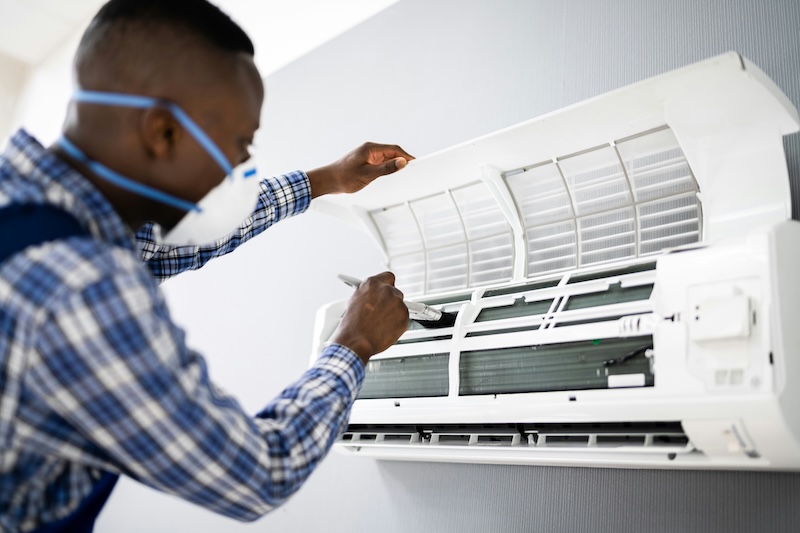 man servicing airconditioner filter, representing service industry.